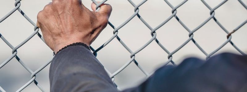 Man's hands gripping a pull-up bar, showing determination.
